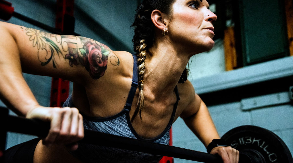 Focused woman lifting weights in a gym, showcasing strength and motivation.