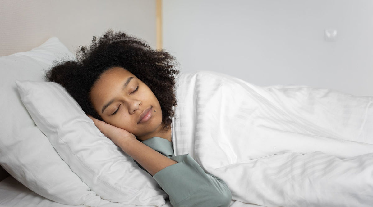 A serene scene of a woman with afro hair peacefully sleeping in a cozy bedroom.